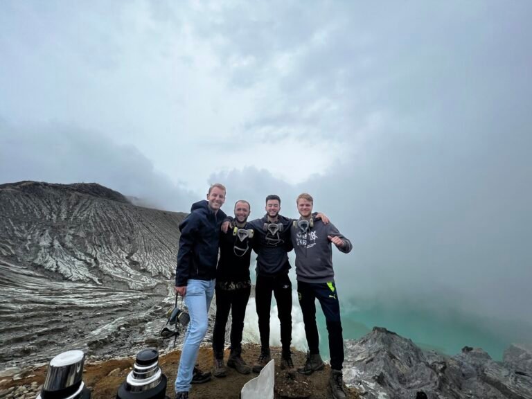 Four travelers overlooking the Ijen crater lake in East Java