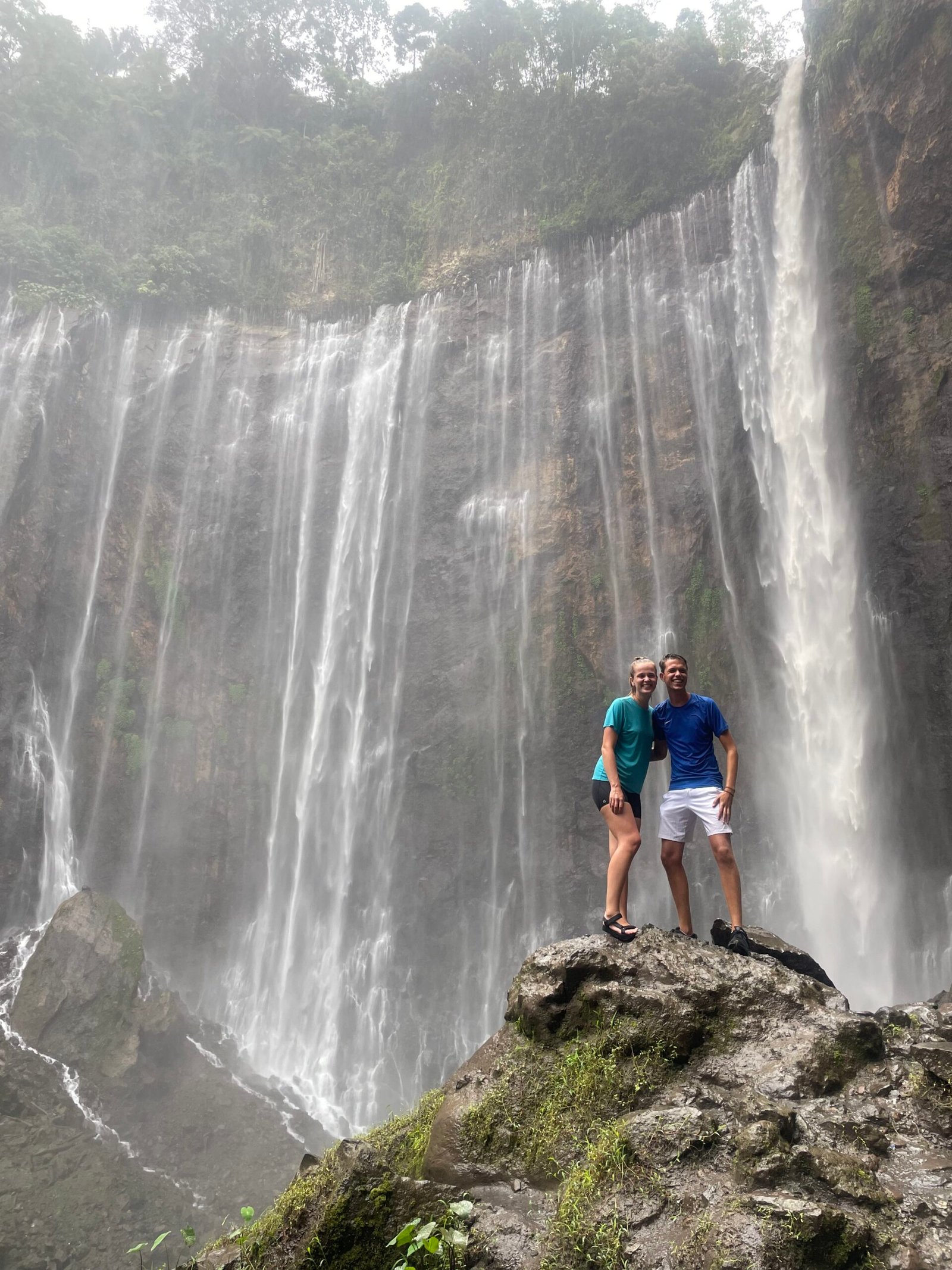 Two travelers standing in front of Tumpak Sewu waterfall in East Java