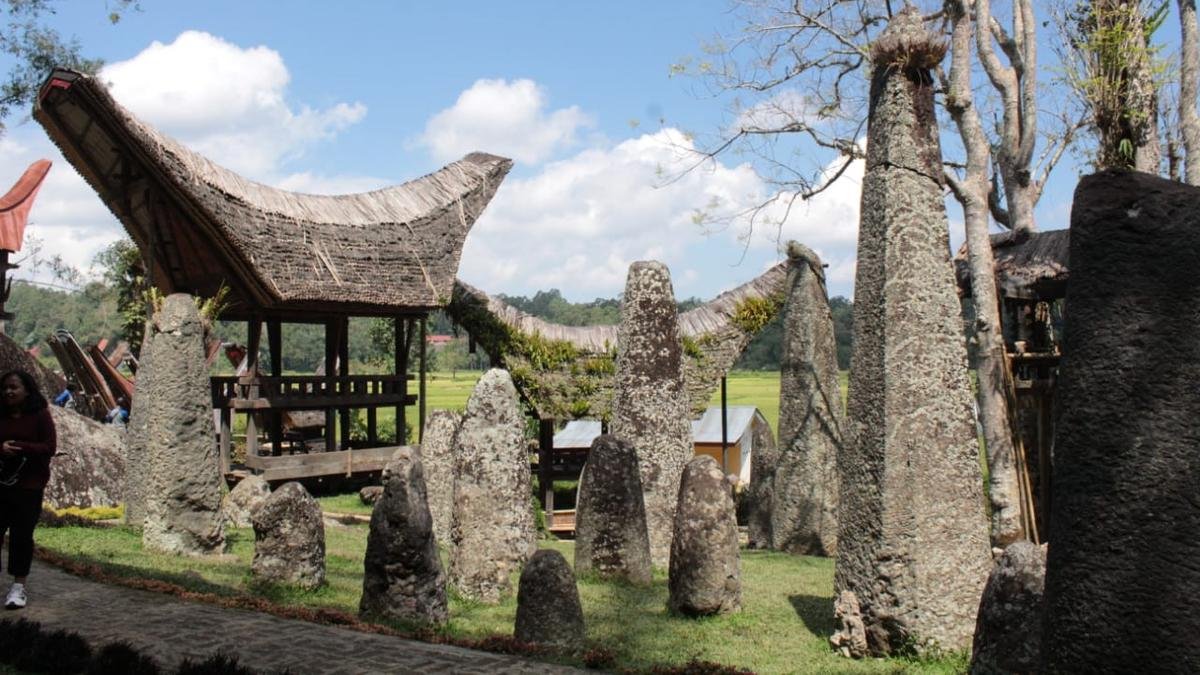 Traditional Torajan house and stone monuments in a green Sulawesi landscape