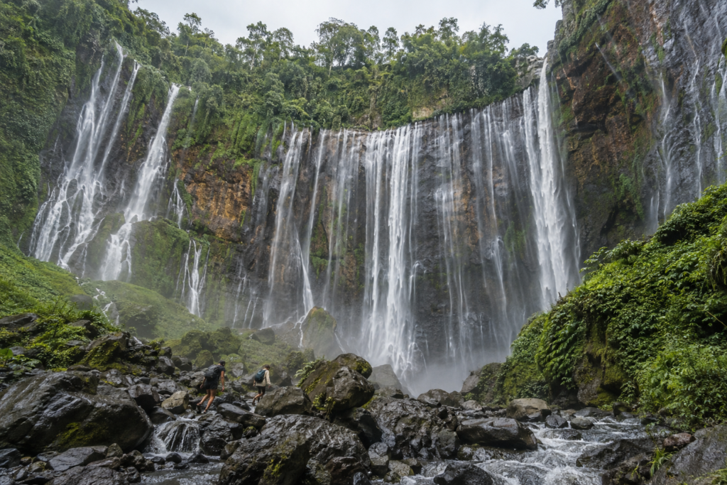Travelers exploring a huge tropical waterfall in East Java.