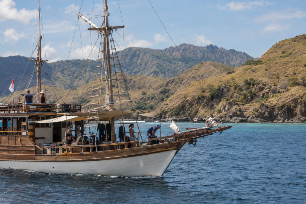 Traditional phinisi liveaboard sailing through Komodo National Park.